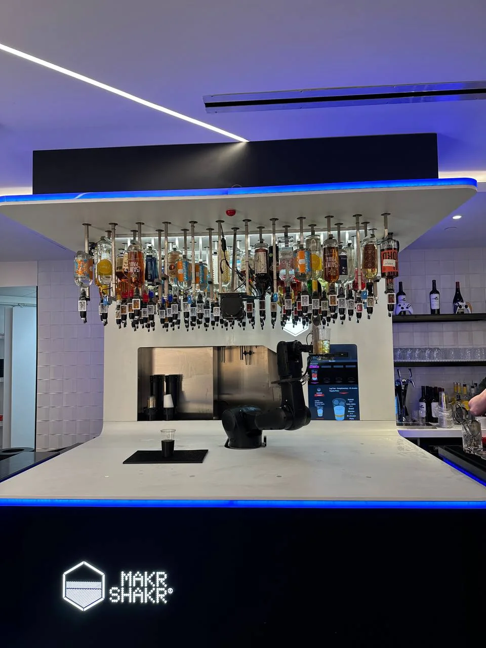 Robot bartender beneath a suspended bottle display in the MSP Portal Lounge