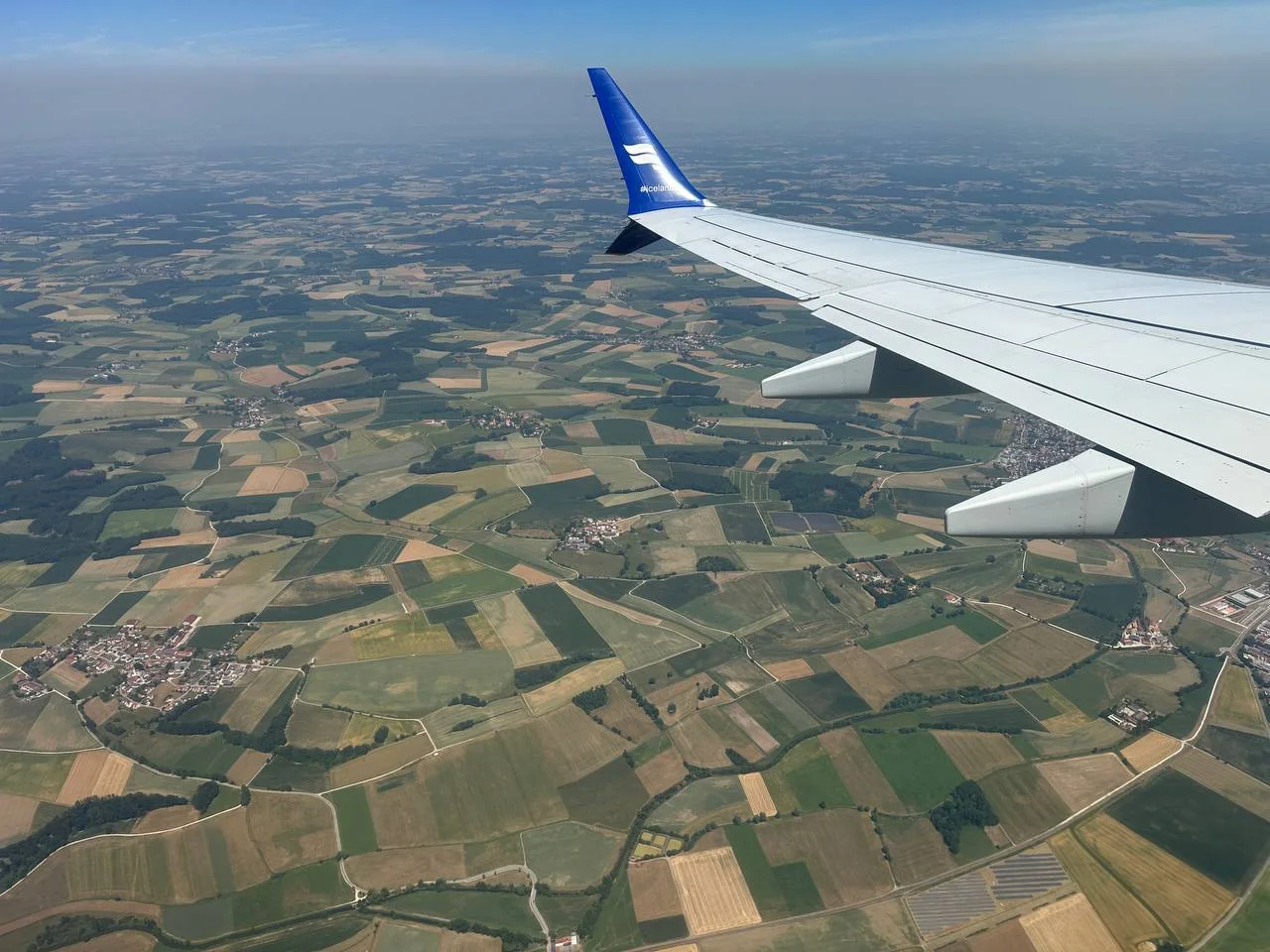 Airplane wing above the green fields of Germany on the approach to Munich
