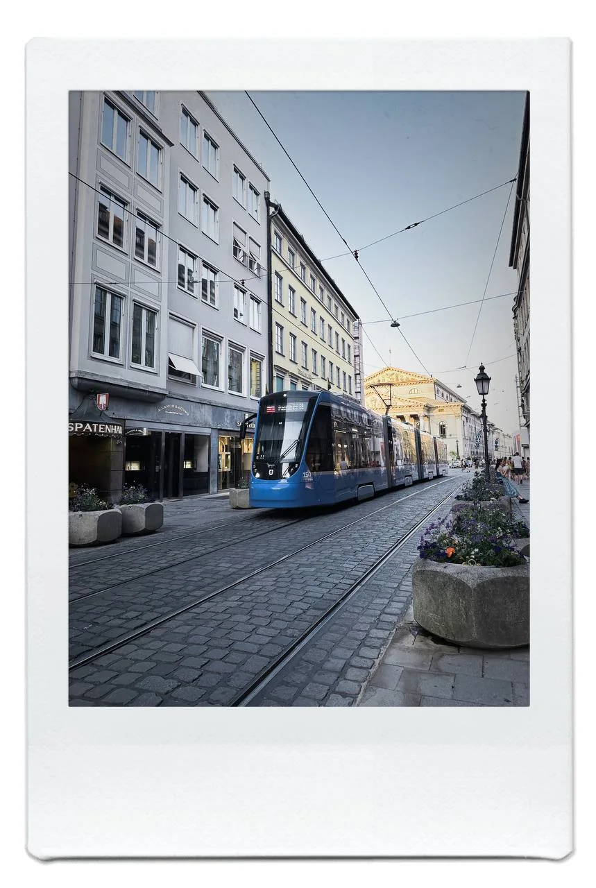 Blue tram traveling through a narrow Munich old-town street