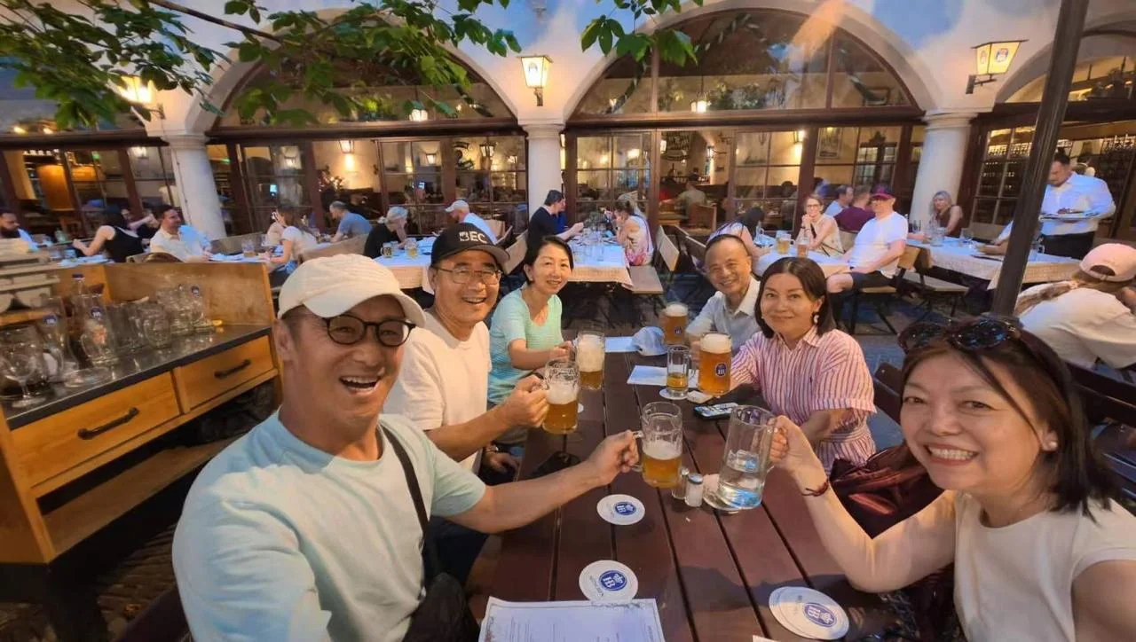 Friends raising glasses around a long dinner table in Munich