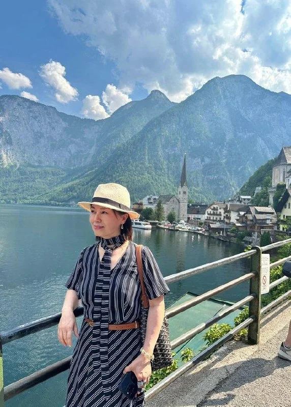 Traveler beside Hallstatt lake with the church spire behind her