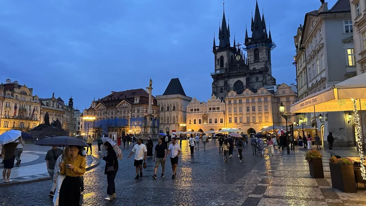Prague Old Town Square glowing at blue hour beneath the towers of the Church of Our Lady before Týn