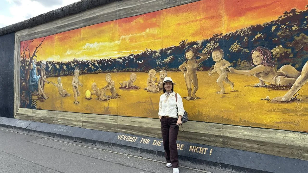 Traveler beside a colorful mural at the East Side Gallery