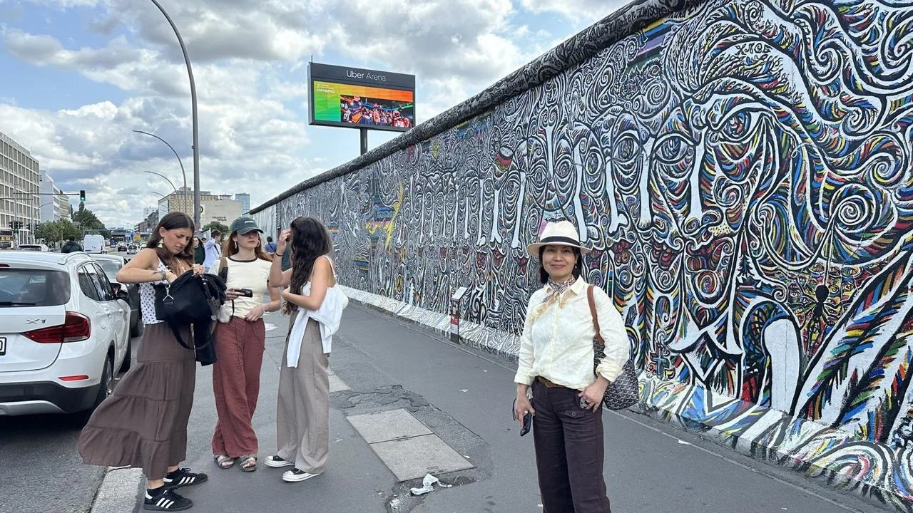 Visitors walking beside murals on the surviving Berlin Wall
