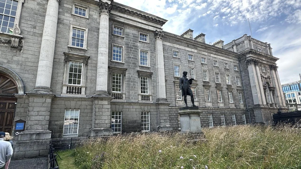 Historic stone facade and campus lawn at Trinity College Dublin
